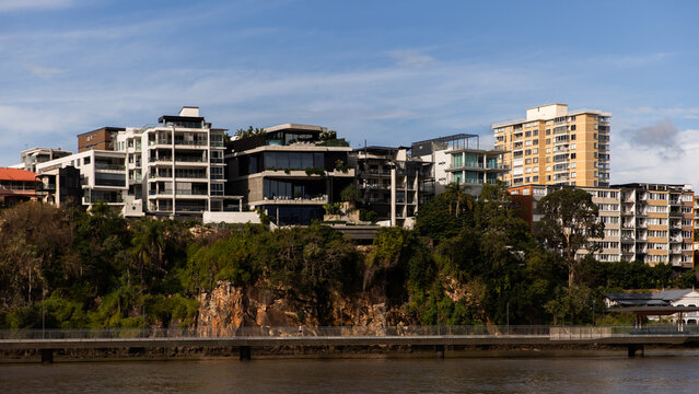 Modern residential and commercial buildings sits atop rocky cliffs covered with greenery