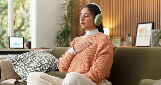 Meditation, breathing and woman with headphones in home for peace, calm and wellness podcast. Breathwork, audio and person in living room on sofa for mindfulness music, relax and zen for self care