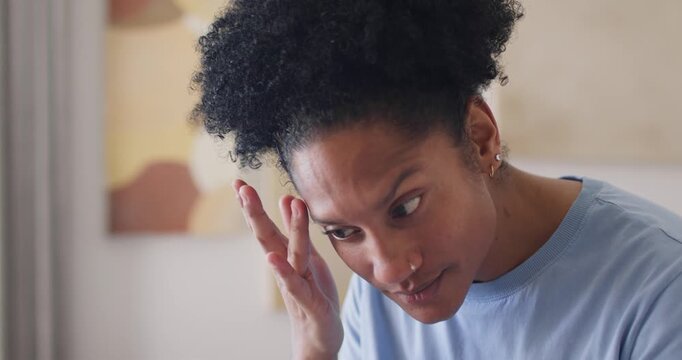 Adult African American female raising right hand, checking eyebrow for spot using compact at vanity