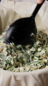 Adding Greek Spinach Feta Pie Filling To Phyllo Dough Pan Close Up Front View Vertical