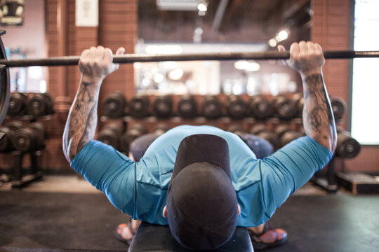 Man with tattooed arms bench pressing barbell