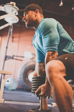 Muscular tattooed man lifting weights at gym