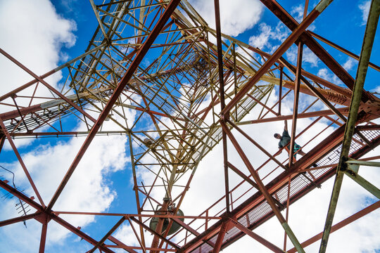 Man climbing a large steel transmission tower from below