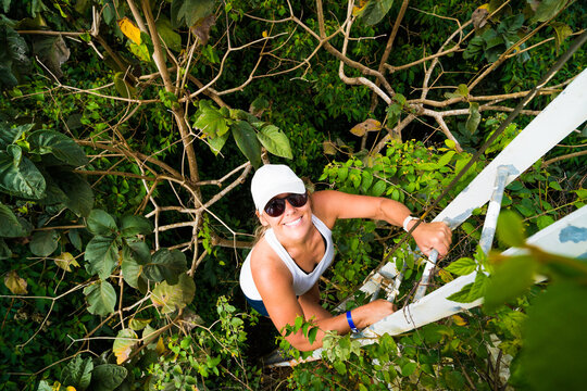 Smiling woman climbing a ladder in the jungle