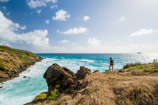 Woman on a scenic cliff trail overlooking ocean
