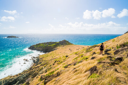 Woman hiking up a grassy hill overlooking the ocean