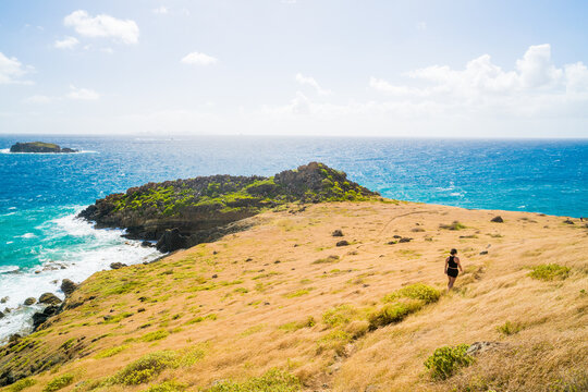 Solo hiker walks down a grassy seaside hill