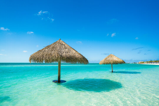 Thatched umbrellas stand in clear turquoise ocean