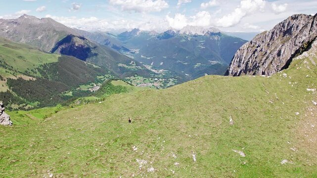 Hiker on Barbarossa ridge in the Bergamo Alps, on background the Dolomites of Val di Scalve
