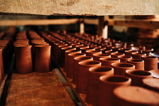 Rows of raw terracotta clay cups drying in workshop