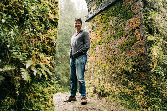 Man smiling hiking between moss covered walls
