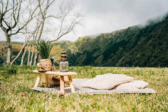 Cozy picnic setup with cushions and lantern in mountain meadow