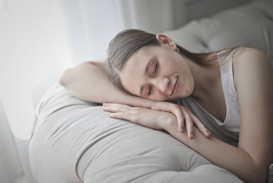 Young woman smiling peacefully while resting on couch