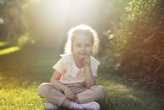 Young girl sitting on grass during golden hour