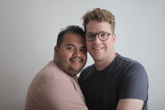 Happy interracial gay couple embracing and smiling