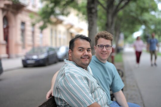 Happy male couple smiling on a city bench