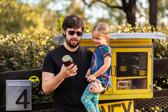 Happy dad with kid buying local honey from roadside stall in Australia