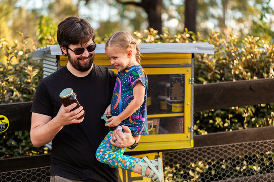 Happy dad with kid buying local honey from roadside stall in Australia