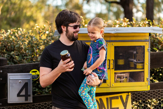 Happy dad with kid buying local honey from roadside stall in Australia