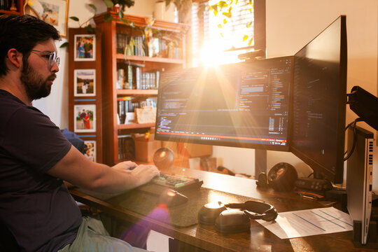 light flare over work from home programmers workspace and desk with ultrawide screens