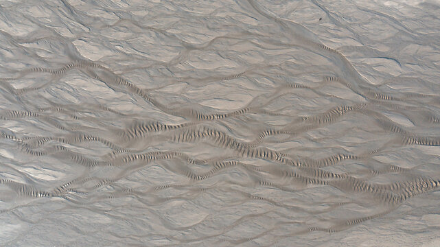 Aerial view of intricate braided sand patterns and ripple textures on the beach at low tide in Mothecombe, Devon, United Kingdom.