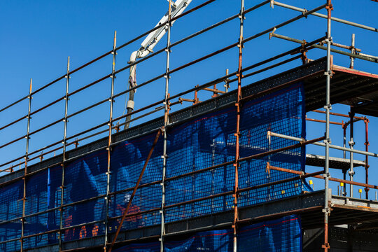 Tradies, safety mesh and scaffold of new building construction site with concrete pump