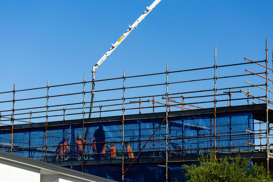 Tradies, safety mesh and scaffold of new building construction site with concrete pump