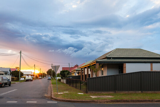 Sunset light peeking from behind clouds down residential road in country town of Singleton