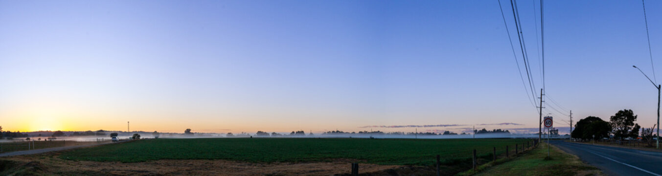 farm landscape scene with mist ribbons settled over distant crop paddock at dawn