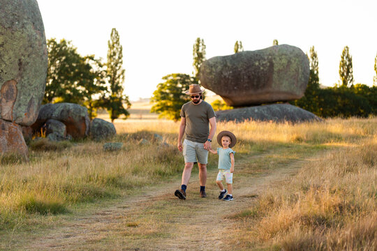 Little Australian girl and her dad on walk in rural paddock reserve wearing Akubra hat