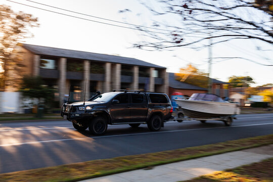 Movement of vehicle towing boat through Australian country town in morning light