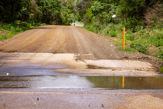 Water over flooded floodway on gravel road