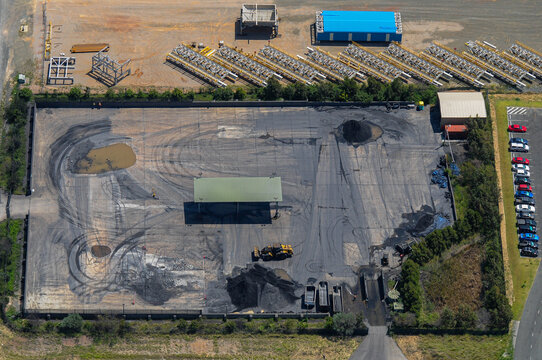 Dusty coal yard with bulldozer and tyre tracks next to shiny equipment