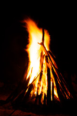 Bonfire with single tall flame above stacked teepee logs night © Ionut Gaspar