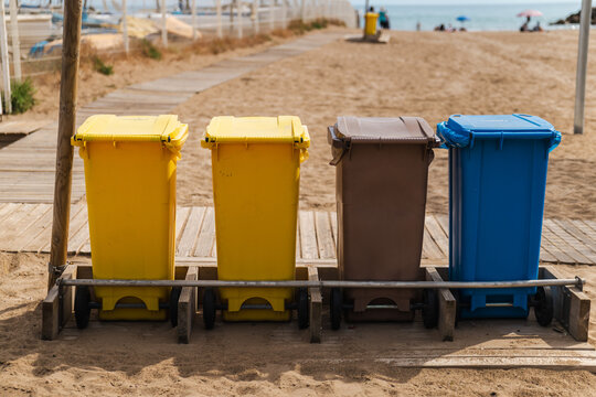 Color coded recycling bins on sandy beach promenade in Sitges Spain