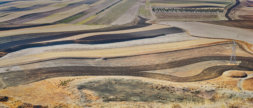 Panoramic elevated view of fallow cereal fields in La Sagra, Toledo, Spain, with dark plots fertilized with wastewater treatment sludge.