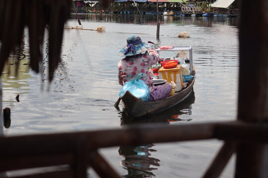Khmer Woman Rowing Loaded Wooden Boat Through Floating Stilt Village on Quiet River at Kien Svay Cambodia