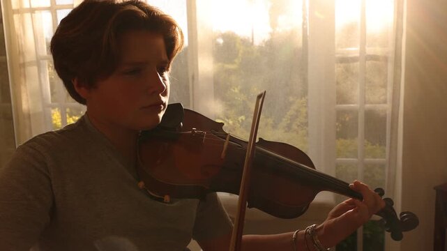 young woman and pre teen boy playing violin in bathroom at sunset