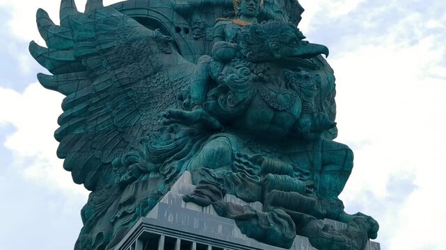 Bali's Most Iconic Landmark Hindu God Garuda Wisnu Kencana statue Cultural Park under a bright blue sky in Bali, Indonesia. traditional Balinese Barong mask with intricate golden carvings.