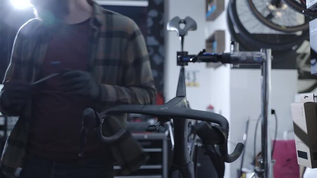 Bike mechanic works on a carbon frame road bike in a premium service shop, adjusting handlebars and components with precision tools for elite cycling maintenance.