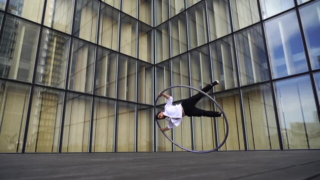Dynamic and vibrant performance of a Cyr Wheel within urban architecture. Concept of individuality, creativity and self-confidence