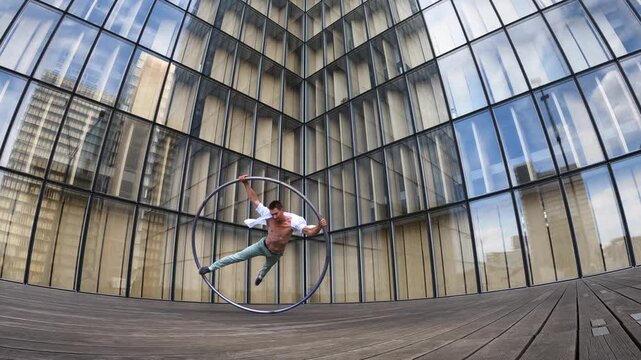Dynamic and vibrant performance of a Cyr Wheel within urban architecture. Concept of individuality, creativity and self-confidence