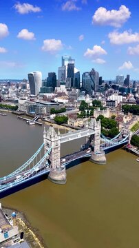 Establishing aerial view of the skyline of London, England, with Tower Bridge, River Thames and City skyscrapers during a summer day