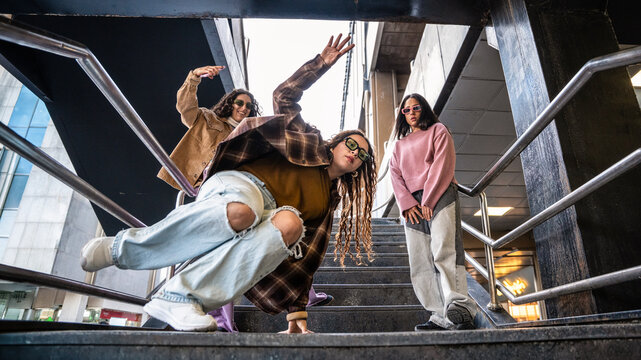 Gen-Z women friends doing street dance on urban stair