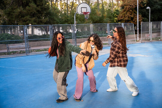 Gen-Z women friends playing basketball on outdoor court