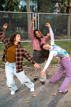 Gen-Z women friends dancing together in an urban park
