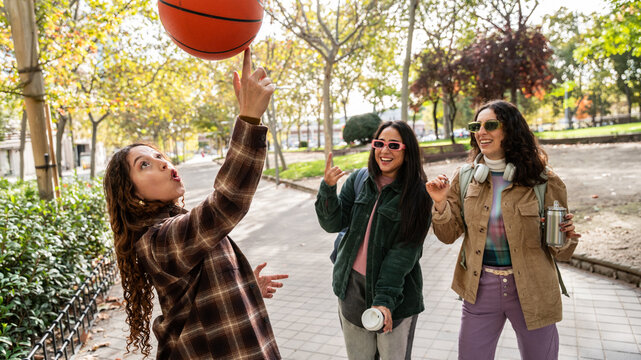 Gen-Z women friends laughing while spinning a basketball