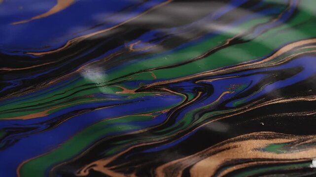 Abstract colorful liquid paint swirl with vibrant blue green and gold flowing patterns in close up