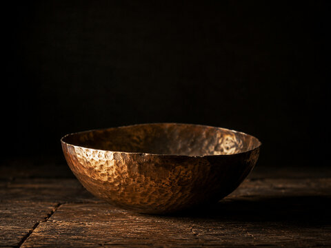Hammered copper bowl with warm patina and rustic texture on wooden surface evoking cozy, vintage kitchen atmosphere