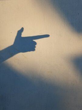 the art of shadow arm gestures on a wall with shadow silhouettes printed on the frame. The finger gun gesture is a hand gesture that imitates the shape of a gun. The goal is to warmly greet a friend, 